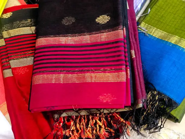 Close up of Colorful traditional Sari, saree displayed in India. natural silk, cotton fold fabric texture. Indian Handloom cotton, hand woven silk with golden designer Border.