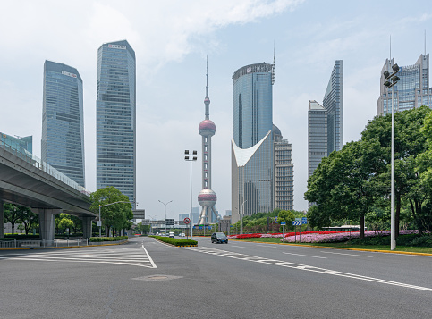 Shanghai, China, June 1st, 2022: Oriental pearl tower near the high-rises, bus and car driving on asphalt road, sunny day