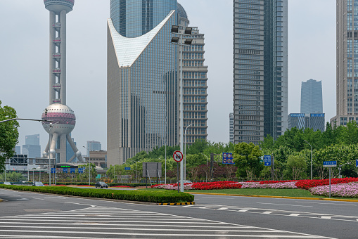 Shanghai, China, June 1st, 2022: Oriental pearl tower near the high-rises, bus and car driving on asphalt road, sunny day