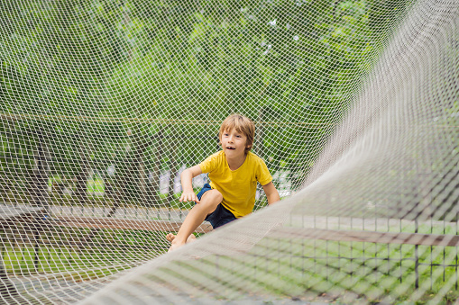 practice nets playground. boy plays in the playground shielded with a protective safety net. concept of children on line, kid in social networks. blurred background, blurred motion due to the concept.