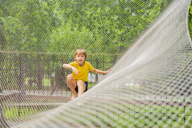 istock practice nets playground. boy plays in the playground shielded with a protective safety net. concept of children on line, kid in social networks. blurred background, blurred motion due to the concept 2082813507