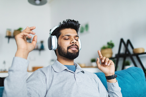 Young adult Indian man listening to music and dancing