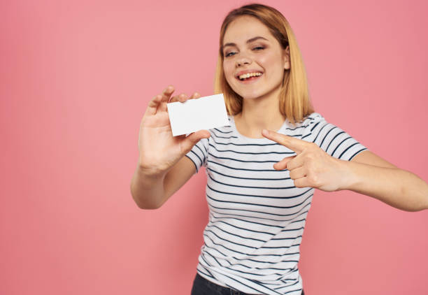istock Woman with white card on pink background gesturing with hands cropped view 2082867851