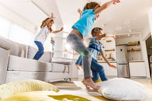 istock Playful kids having fun while jumping from sofa at home. 2082870007