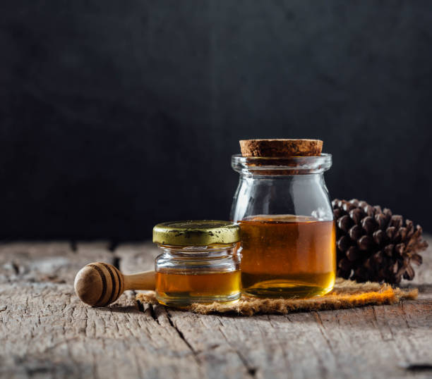 Honey in a glass bottle on a wooden background stock photo