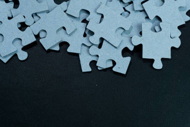 Stacked unfinished puzzle pieces on black background