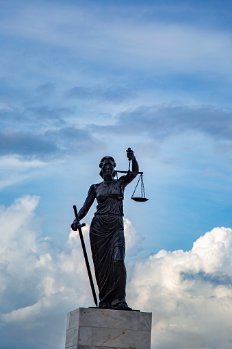 Sculpture of Lady Justice or Themis symbol of justice and law, Femida outdoors against blue cloudy sky background copy space vertical