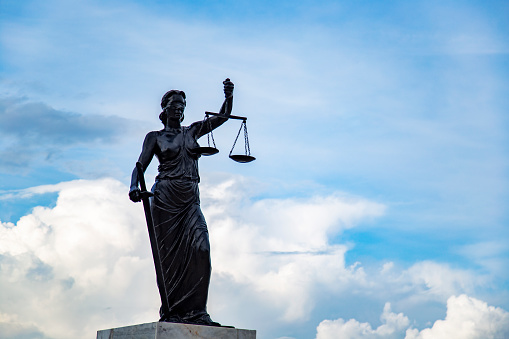 Sculpture of Lady Justice or Themis symbol of justice and law, Femida outdoors against blue cloudy sky background copy space