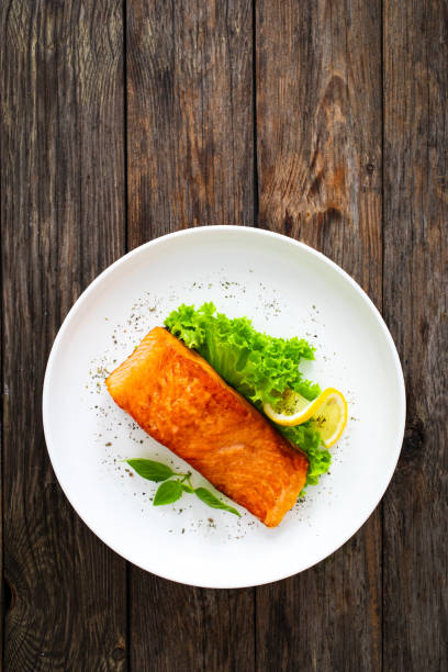 istock Seared salmon steak with fresh vegetables on wooden table 2082923173