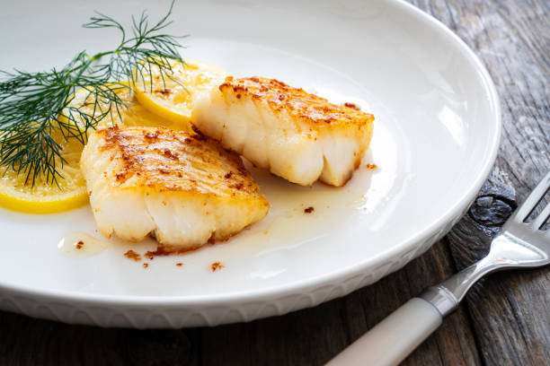 istock Fried codfish loin, lemon slices and dill on wooden table 2082930051