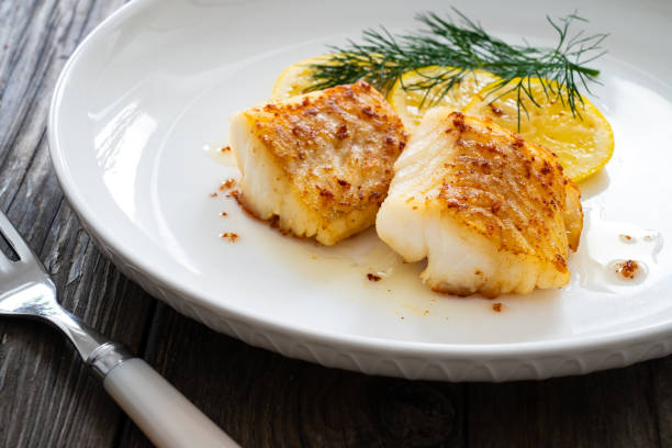 istock Fried codfish loin, lemon slices and dill on wooden table 2082931114