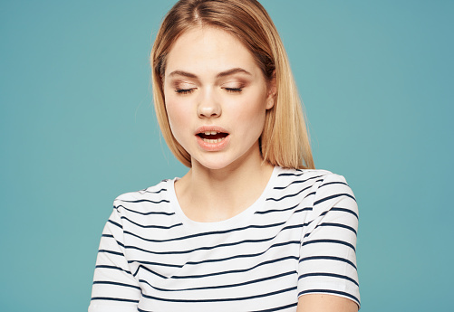 Woman model in striped t-shirt indignant look emotions blue background. High quality photo