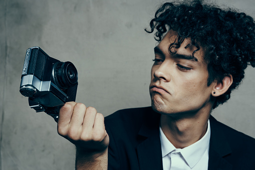 stylish man with camera in hand photography studio curls model portrait. High quality photo