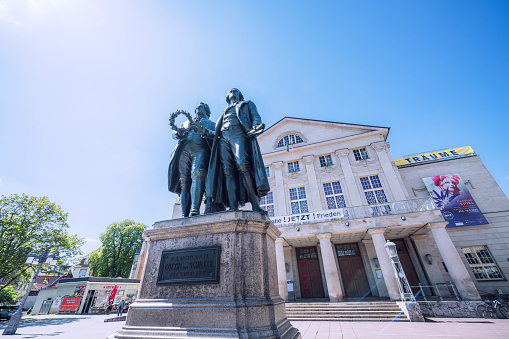 Editorial photo of the iconic Goethe-Schiller Monument in front of the Deutsches Nationaltheater on a bright day in Weimar, Germany, May 3, 2023.