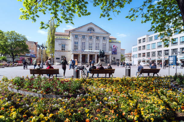 Editorial photo of people enjoying a sunny day at a vibrant Weimar square with historical architecture on May 3, 2023, in Germany.