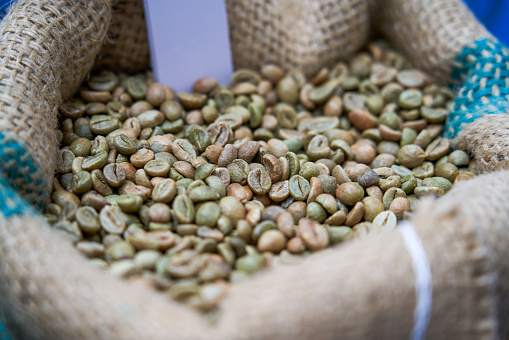 A bag of unroasted green coffee beans close-up
