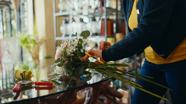 Closeup of Female Florist Tying Thread to Make Beautiful Bouquet of Flowers in Shop