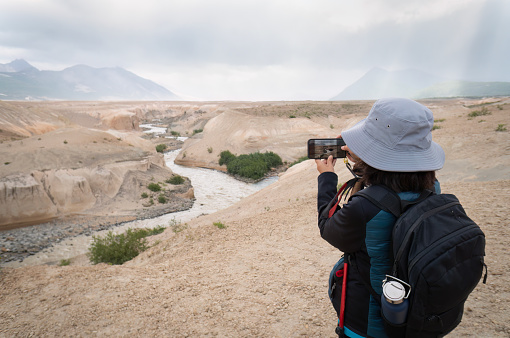 Canyon cut by river at Valley of Ten Thousand Smokes. Woman taking photos using smartphone.
Katmai National Park and Preserve. Alaska. USA.