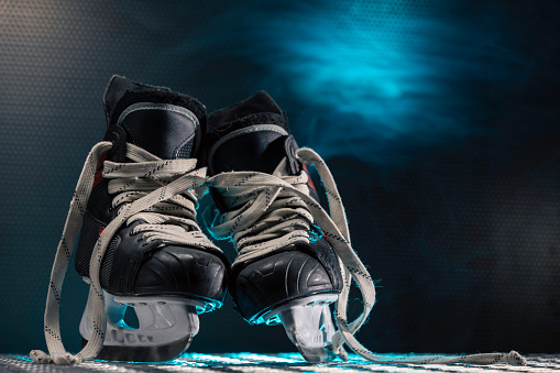Hockey skates and space for text on ice rink background.