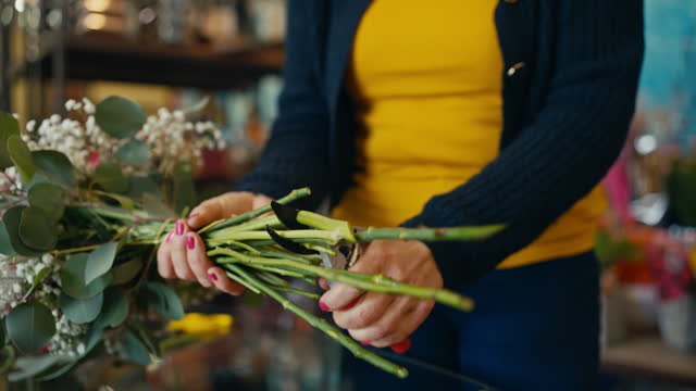 Closeup of Female Florist Cutting Stems of Beautiful Flowers while Making Bouquet in Shop