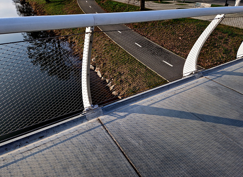 stainless steel mesh stretched on bridge railing.lower steel rope serves as barrier to water drain. the wheelchair user does not have to crash, bike is guided by a cable on side, path, road marking