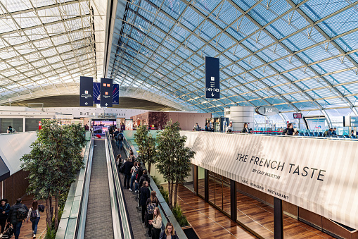 Editorial photo of the bustling terminal inside Paris Charles De Gaulle Airport, showcasing passengers and retail areas, taken on November 1, 2022.