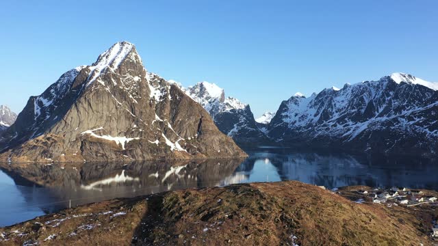 Norway. Lofoten Islands. Aerial view. Breathtaking bird's eye view of mountain rocky peaks covered with white snow reflected in sea water. Panoramic fjords landscape of Lofoten in winter.