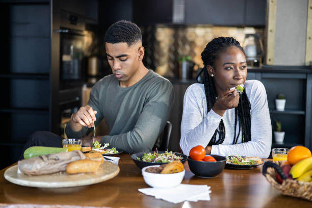 African American couple ignoring each other during a meal at home.