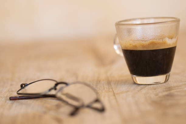 A serene coffee setup featuring a cup, saucer, creamer, and sugar bowl alongside stylish glasses on a rustic wooden table, perfect for a cozy morning ritual.
