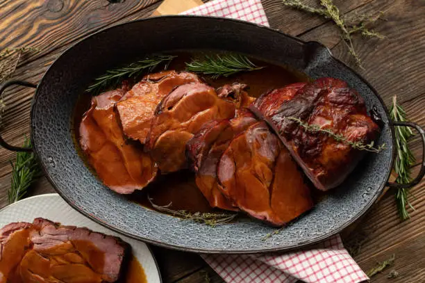 German roast pork with delicious brown gravy or sauce on rustic and wooden table background. Traditional kasseler roast.
