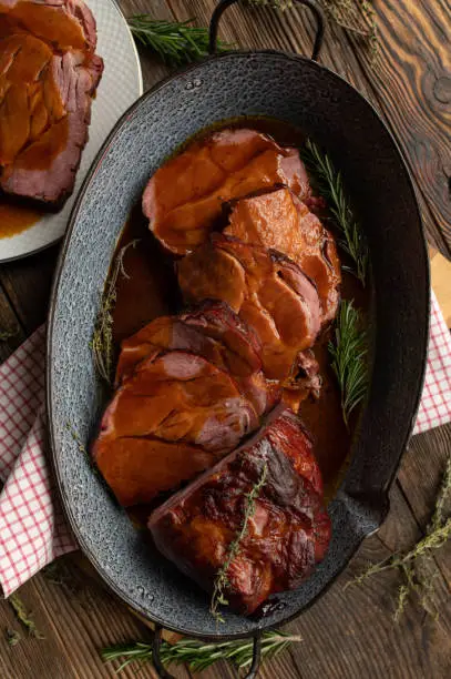 German pork roast with delicious brown sauce. Traditional and rustic cuisine. Served ready to eat in a roasting pan on wooden table background.