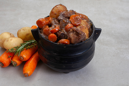 Traditional South African pot (potjie). Stew cooked in cast iron pot over open flames.
Beef potjie with vegetables on mottled grey with copy space