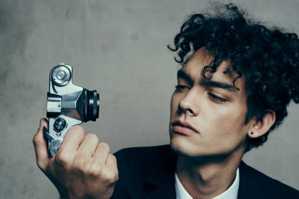 stylish man with camera in hand photography studio curls model portrait. High quality photo
