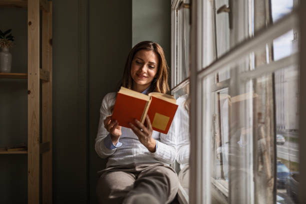 istock Businesswoman Enjoying Book on Window Ledge 2083029143