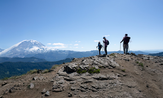Three people enjoying the views on the Summit Lake trail. Snow-capped Mount Rainier in the background. Mt Rainier National Park. Washington State.