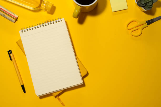 istock Blank spiral notepad, water bottle and stationery on yellow background with copy space 2083038888