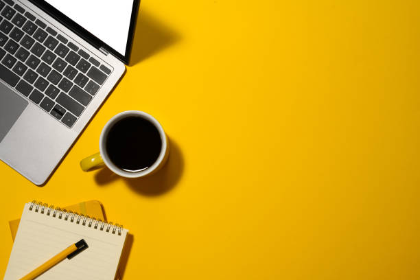 istock Laptop, cup of coffee and blank notepad on yellow background with copy space 2083038889
