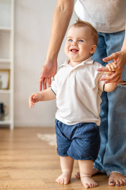 istock Man Holding Babys Hand on Hardwood Floor 2083040577