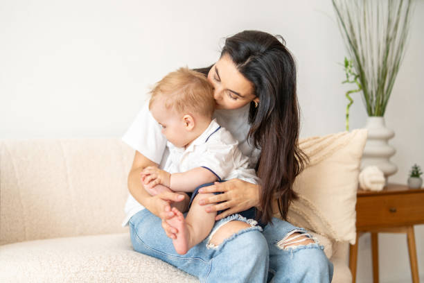 istock Woman Sitting on Couch Holding Baby 2083040588