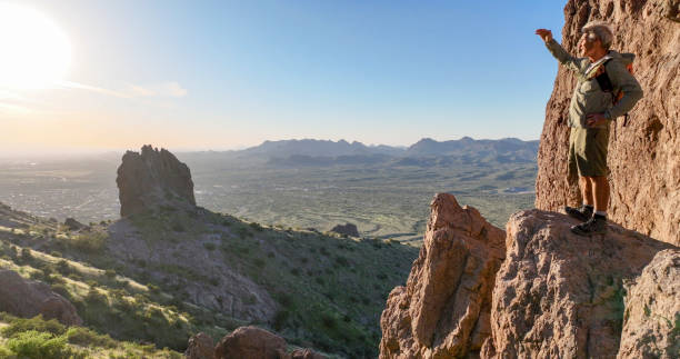 istock Hiker stands on rock pinnacle above desert 2083060740