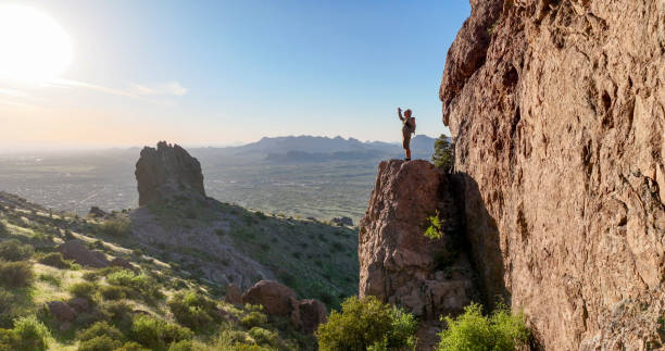 hiker stands on rock pinnacle above desert - side view southwest usa horizontal sun стоковые фото и изображения