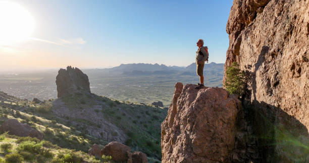 istock Hiker stands on rock pinnacle above desert 2083061804