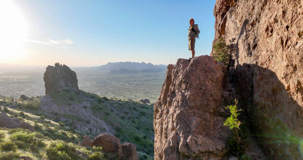 istock Hiker stands on rock pinnacle above desert 2083062334