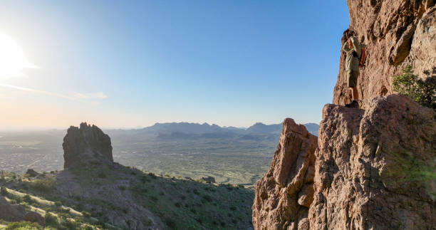 istock Hiker stands on rock pinnacle above desert 2083063389