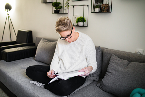 Happy woman reading book on couch at home