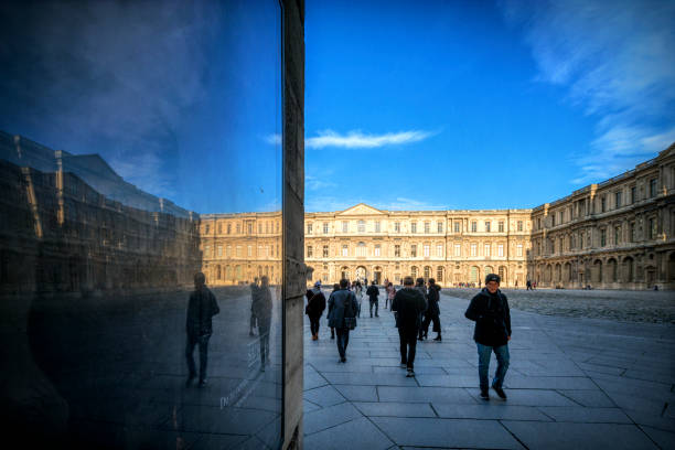The Arc de Triomphe de Carrousel in Paris France, in the foreground are tourists walking from the Louvre museum.