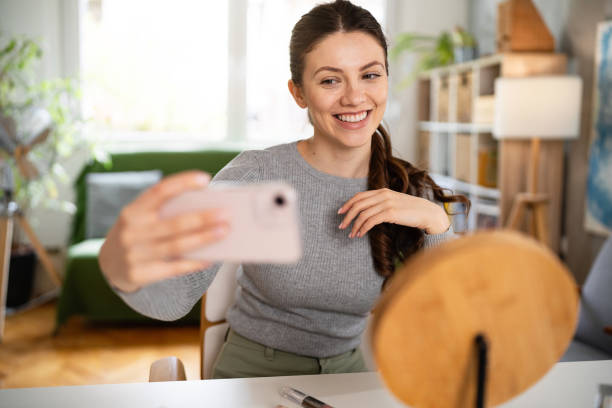istock Young woman taking selfie while doing make-up at home 2083080924