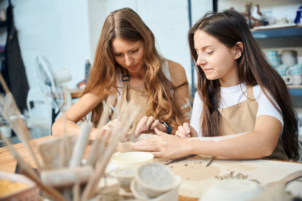 istock Women artists working with clay shaping handmade dishes in pottery workshop 2083086797