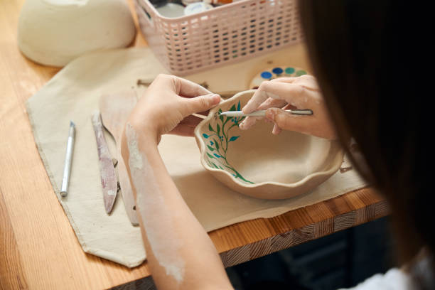 istock Unrecognizable woman painting clay bowl in workshop 2083087151