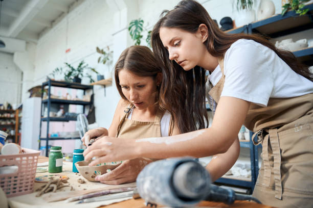 istock Females ceramists carving pottery in ceramic workshop 2083087325